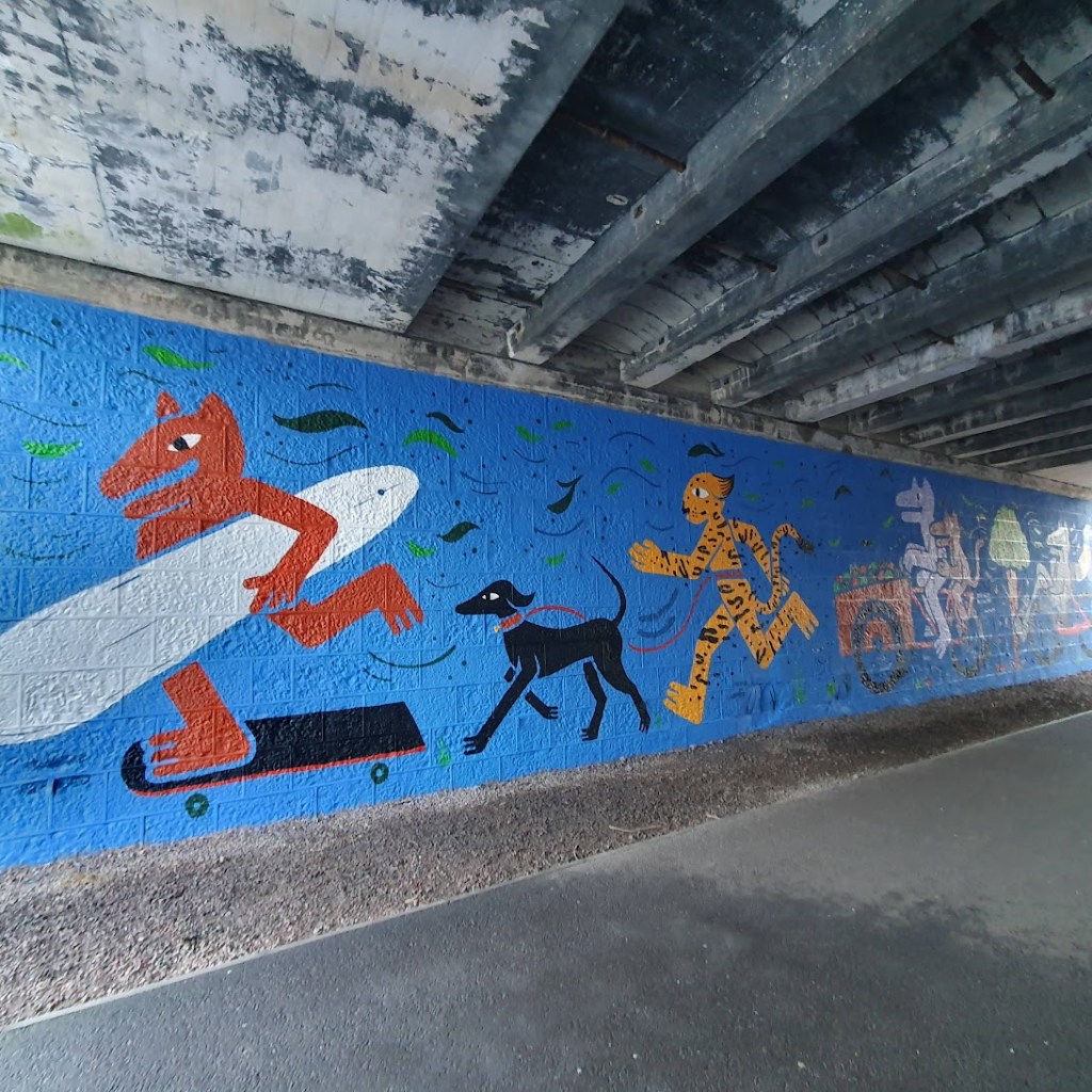 Paint wall showing the surfer on a skateboard carrying his surfboard and the leopard running with a black dog.